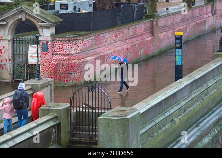 Un piéton muni d'un parapluie drapeau de l'Union passe devant les cœurs rouges sur le mur commémoratif national Covid, dans le centre de Londres. Banque D'Images