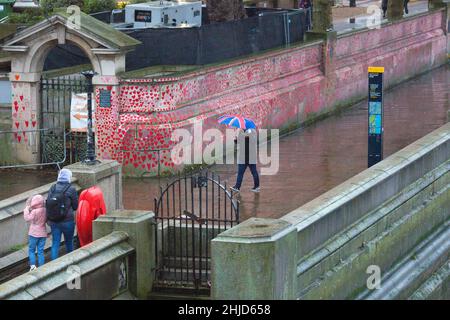 Un piéton muni d'un parapluie drapeau de l'Union passe devant les cœurs rouges sur le mur commémoratif national Covid, dans le centre de Londres. Banque D'Images