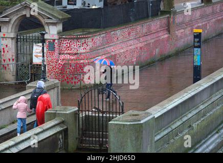 Un piéton muni d'un parapluie drapeau de l'Union passe devant les cœurs rouges sur le mur commémoratif national Covid, dans le centre de Londres. Banque D'Images