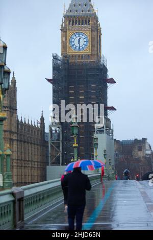 La tour Elizabeth, communément appelée Big Ben, est considérée comme un piéton tenant un drapeau de l'Union marche le long du pont de Westminster dans le centre de Londres. Banque D'Images