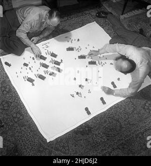 Soldats de l'étain dans les 1950s.Les membres des collectionneurs danois de figurines en étain se sont rassemblés autour des jouets en étain sur le sol et ont l'air heureux d'eux.Sigurd Koch joue à droite et déjoue actuellement l'une des plus belles collections de soldats et de jouets en étain.Les soldats de l'étain étaient un passe-temps historique souvent dans les thèmes.L'étain a été fondu et versé sous forme de figures qui, lorsqu'ils avaient refroidi et pris hors des formes ont été peintes avec soin.1952. Kristoffersson réf. BE30-7 Banque D'Images