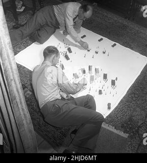 Soldats de l'étain dans les 1950s.Les membres des collectionneurs danois de figurines en étain se sont rassemblés autour des jouets en étain sur le sol et ont l'air heureux d'eux.En haut de la photo est Sigurd Koch qui, à cette époque, détestait l'une des plus belles collections de soldats et de jouets en étain.Les soldats de l'étain étaient un passe-temps historique souvent dans les thèmes.L'étain a été fondu et versé sous forme de figures qui, lorsqu'ils avaient refroidi et pris hors des formes ont été peintes avec soin.1952. Kristoffersson réf. BE30-8 Banque D'Images