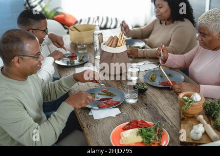 Bonne famille afro latine manger un déjeuner sain avec des légumes frais À la maison - concept de l'unité de la nourriture et des parents Banque D'Images