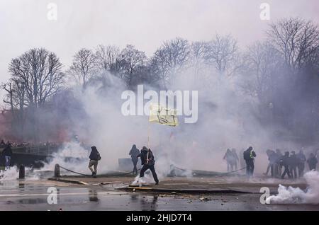 Un manifestant a un drapeau au milieu de la fumée de téargas pendant la manifestation.la fin de la manifestation de dimanche dans la ville belge de Bruxelles et au cœur de l'Union européenne a été marquée par une petite minorité qui n'a que pour but la violence.Plus de 50 000 manifestants venus de toutes les parties de l'Europe ont participé à une manifestation contre le coronavirus anti-gouvernement, qui s'est passée sans incident.Une violente minorité vêtue de noir, a renversé le district européen, ont vandalisé des voitures, des pierres ont été catapulté et lancées et des panneaux de signalisation ont été déracinés, l'avant du bâtiment du « Service européen pour l'action extérieure » de l'EEAS était totalement Banque D'Images