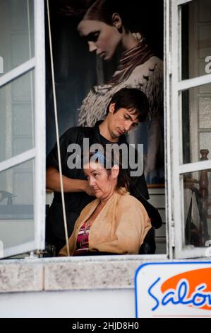 Le coiffeur masculin fait les cheveux de la femme dans un salon pour les femmes en face de l'hôtel Havana libre à la Havane, Cuba. Banque D'Images