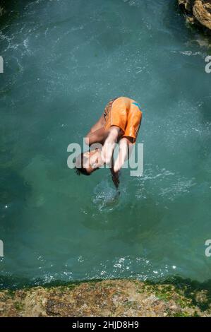 Un jeune garçon sautant dans les eaux océaniques le long de la Malécone à la Havane, Cuba. Banque D'Images