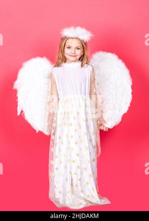 Ange enfant avec ailes blanches et anges halo, jour de la Saint Valentin.Angélique enfants fille, isolé rouge studio arrière-plan avec espace de copie. Banque D'Images