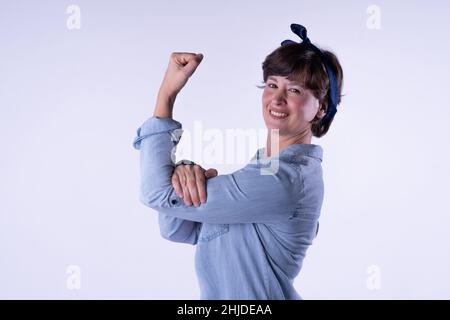 Portrait en gros plan d'une jolie femme souriante en vue latérale.Fille à poil court montrant un muscle de bras fort isolé sur fond blanc Banque D'Images