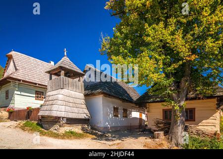 Clocher en bois dans une rue avec d'anciennes maisons colorées dans le village de Vlkolinec, Slovaquie, Europe. Banque D'Images