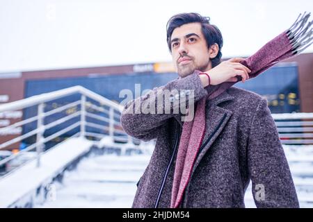 Jeune homme arabe barbu avec une coiffure moderne en manteau avec foulard en laine Banque D'Images