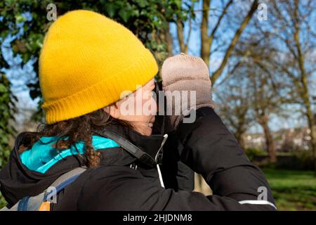 Personne avec un chapeau et des gants d'observation des oiseaux lors d'une journée d'hiver ensoleillée dans la nature Banque D'Images
