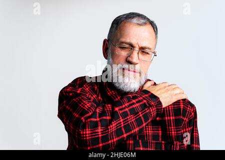 Portrait d'un homme mature isolé sur fond gris souffrant de douleurs corporelles graves, fermant les yeux pour soulager la douleur Banque D'Images