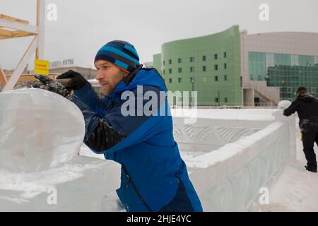 Un sculpteur sculpta une boule de glace ronde sur un bloc de glace avec un burin. Banque D'Images