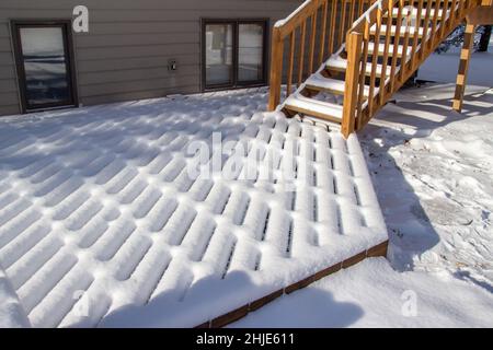 Vue extérieure sur les motifs de neige fraîche sur une terrasse et un escalier en bois, en hiver avec la lumière naturelle du soleil Banque D'Images