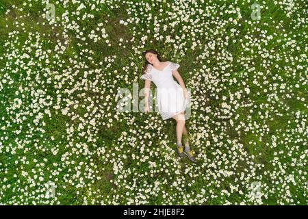 Belle fille se trouve dans la camomille Marguerite fleur.Vue de dessus.Photographie aérienne. Banque D'Images