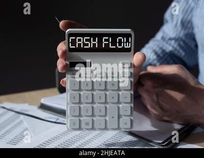 Mot de flux de trésorerie sur la calculatrice blanche dans les mains des hommes.Déclaration de flux de trésorerie dans le bras comptable. Banque D'Images