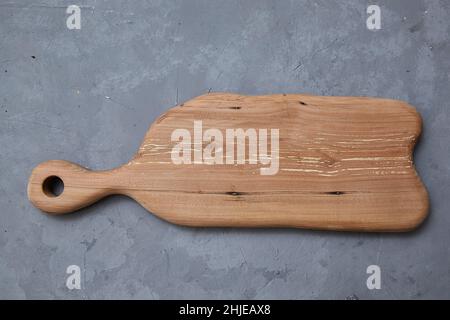 La planche à découper en bois vide repose sur un fond gris. Vue du dessus, espace de copie. Banque D'Images