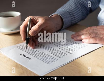 Homme lisant le contrat pour le signer au bureau. Banque D'Images