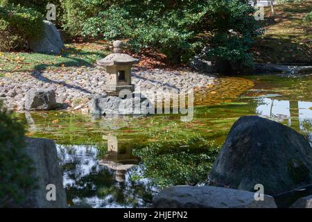 Vue sur la lanterne traditionnelle en pierre de toro au bord de l'étang, au jardin du château de Nagoya.Japon Banque D'Images