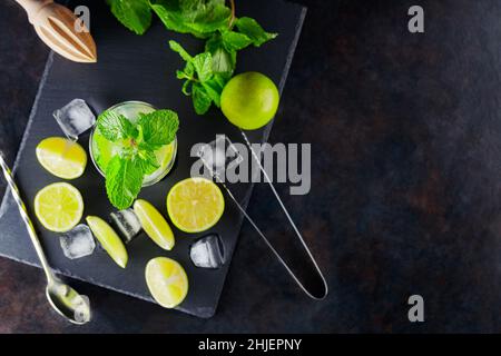 Cocktail Mojito et ingrédients sur fond sombre.Mojito à cocktail rafraîchissant sur un tableau d'ardoise.Concept cocktail d'été avec citron vert et menthe.Top vie Banque D'Images