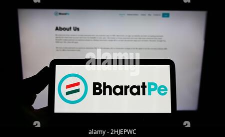 Personne portant un smartphone portant le logo de la société Resilient innovations Pvt.Ltd. (BharatPe) à l'écran devant le site Web.Mise au point sur l'affichage du téléphone. Banque D'Images