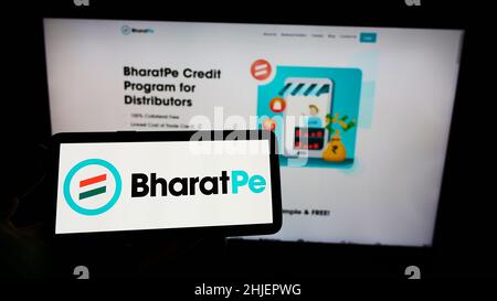 Personne tenant un téléphone portable avec le logo de la société Resilient innovations Pvt.Ltd. (BharatPe) à l'écran en face de la page Web.Mise au point sur l'affichage du téléphone. Banque D'Images
