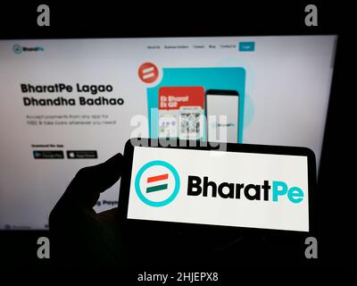 Personne tenant un téléphone portable portant le logo de la société Resilient innovations Pvt.Ltd. (BharatPe) à l'écran en face de la page Web.Mise au point sur l'affichage du téléphone. Banque D'Images