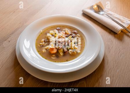 Soupe de légumes italienne minestrone dans une assiette blanche avec cuillère sur une table en bois Banque D'Images