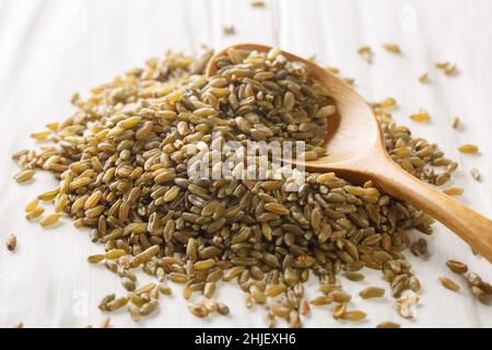 Cuillère en bois avec grains de Freekeh rôtis sur table rustique blanche.Horizontale Banque D'Images