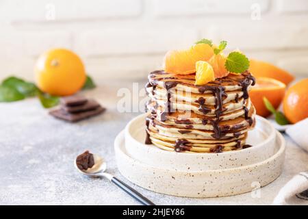 Fête du Pancake, petit déjeuner sain.Délicieuses crêpes américaines maison à la banane avec chocolat et orange rouge sur fond de pierre grise.Copier Banque D'Images