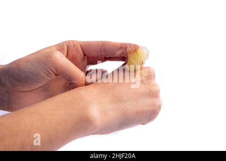 Femme appliquant de la vaseline sur sa main isolée sur fond blanc.Jeune fille faisant des soins de la peau avec la crème hydratante. Banque D'Images