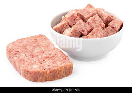 Viande de porc coupée en dés dans un bol en céramique blanc à côté d'une tranche de viande de porc isolée sur blanc. Banque D'Images