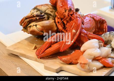 Le pagurus du cancer a cuit le crabe, le homard canadien, les pétoncles frais crus et les crevettes fraîches crues sur un plan de cuisine en bois Banque D'Images