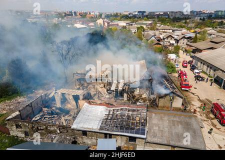 Vue aérienne des pompiers l'extinction a ruiné le bâtiment sur le feu avec le toit écrasé et la montée de fumée sombre. Banque D'Images