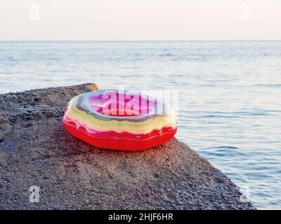 Un anneau de natation gonflable multicolore et lumineux se trouve au bord du brise-lames près de la mer Banque D'Images