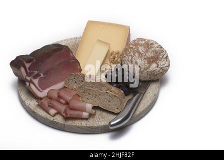 Délicieux et savoureux loin bacon fromage raisins noix pain traditionnel du Tyrol du Sud et couteau à grignoter sur une planche en bois clair devant un fond blanc Banque D'Images
