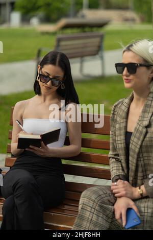 Femme d'affaires écrit les nouveaux plans pour l'entreprise tandis que l'autre parle à elle Banque D'Images