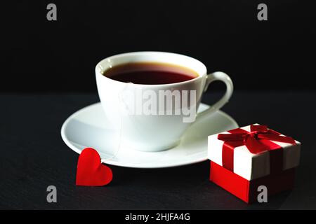 Tasse de thé blanche sur fond noir.Sachets de thé en forme de coeur.Mise au point sélective. Banque D'Images