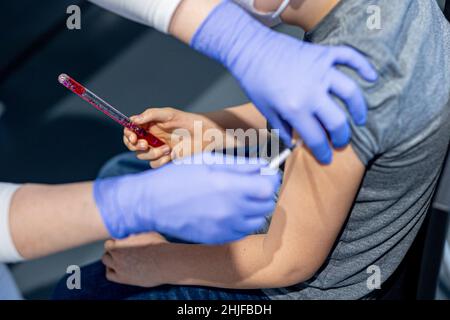 Wolfsburg, Allemagne.29th janvier 2022.Julius est vacciné contre le coronavirus au phaeno Wolfsburg, tenant une 'baguette magique' dans sa main comme une distraction (scène posée).Une campagne de vaccination des enfants pour contenir le coronavirus a lieu au musée de l'aventure.Tous les enfants et les jeunes ainsi que les membres de leur famille d'accompagnement devraient recevoir l'admission gratuite au phaeno après la vaccination.Credit: Moritz Frankenberg/dpa/Alay Live News Banque D'Images