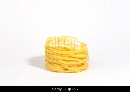 Pâtes italiennes.Spaghetti Capellini isolé sur fond blanc avec des ombres dures.Pâtes sous forme de nids.Photo créative des pâtes alimentaires. Banque D'Images