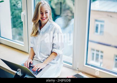 Bonne femme indépendante travaillant sur l'ordinateur dans l'espace de travail Banque D'Images