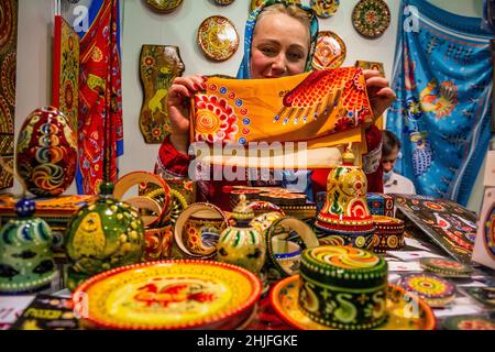 Moscou, Russie.18th décembre 2021 Une vendeuse présente les peintures traditionnelles de Vyatka dans une boutique de souvenirs à l'exposition-salon de l'artisanat folklorique de Russie 'Ladya' à l'Expocentre de Moscou, Russie Banque D'Images