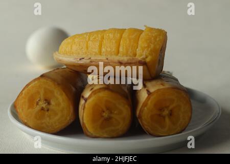 Banane plantain vapeur avec œuf dur en arrière-plan.Prise de vue sur fond blanc Banque D'Images