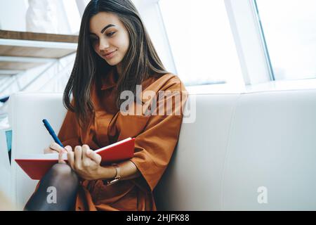 Bonne jeune femme prenant des notes sur le journal Banque D'Images