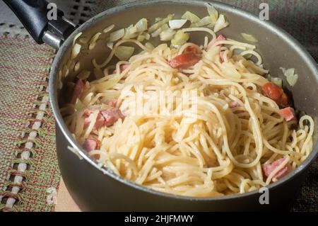 nouilles dans une casserole avec saucisse de calabresa et crème aigre, nouilles carbonara en préparation. Banque D'Images