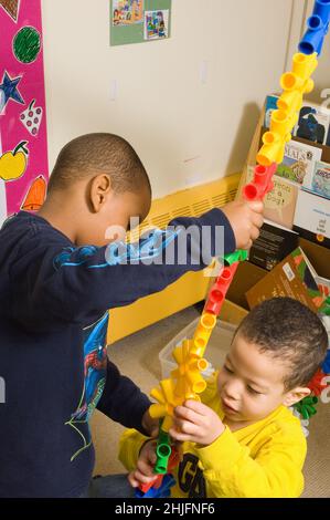 Éducation préscolaire salle de classe 3-4 ans deux garçons construisant un morceau très grand à partir de pièces en plastique coloré de connexion Banque D'Images