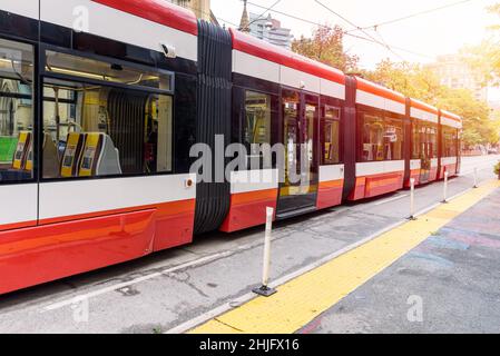 Tram laissant un arrêt le long d'une rue dans un centre-ville lors d'une journée d'automne ensoleillée Banque D'Images