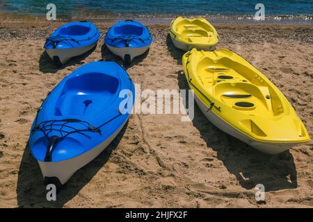 Des bateaux de kayak bleu et jaune vif sur une plage près de l'eau de mer.Canoë pour les activités estivales. Banque D'Images