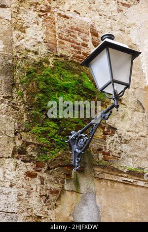 Une célèbre lanterne de rue sur un vieux mur avec de la mousse verte à Asciano, province de Sienne Banque D'Images