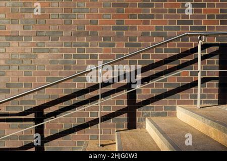 les balustrades graphiques et les ombres contre un mur de briques dirigent la lumière sans personne Banque D'Images